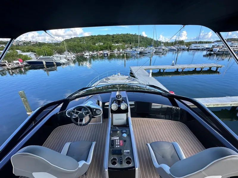 Slide: The Image of 2023 Sunseeker 65 Sport Yacht cockpit overlooking marina with lush green backdrop. - 22