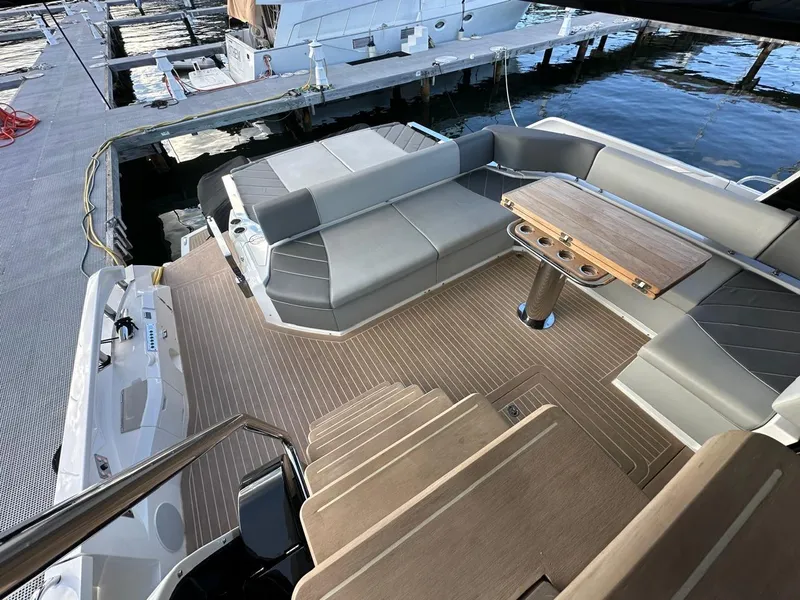 Slide: The Image of 2023 Sunseeker 65 Sport Yacht deck with seating and table, docked at marina. - 23