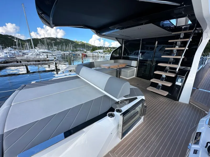 Slide: The Image of 2023 Sunseeker 65 Sport Yacht deck with seating, table, and marina view. - 24
