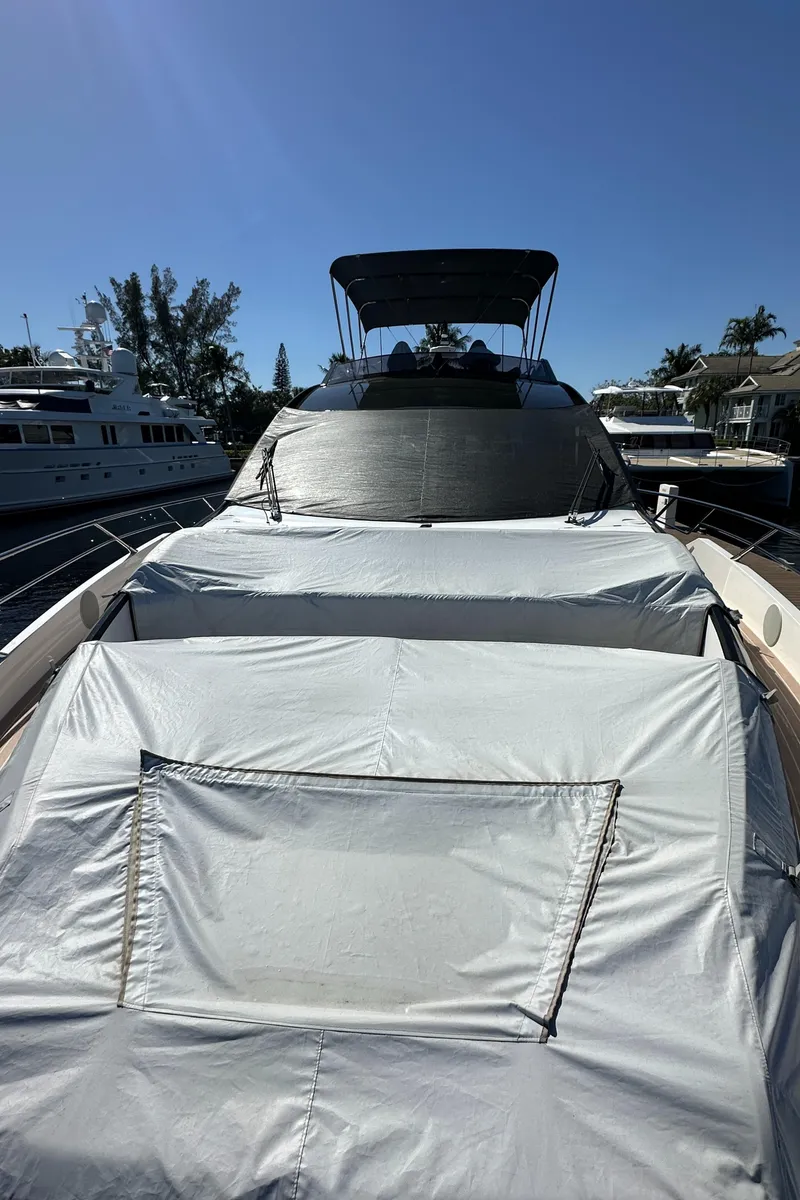 Slide: The Image of 2023 Sunseeker 65 Sport Yacht docked, covered with protective tarps under clear blue sky. - 44