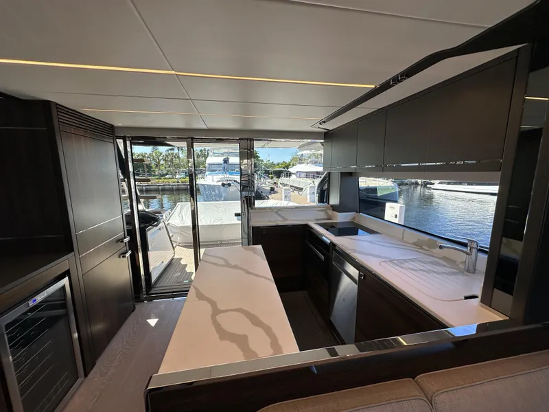 Slide: The Image of Interior of 2023 Sunseeker 65 Sport Yacht, featuring modern kitchen and marina view. - 9