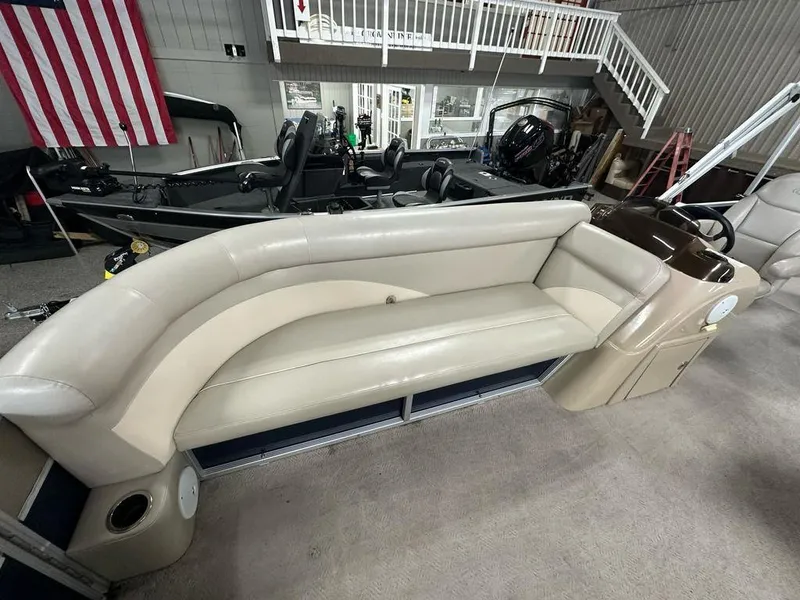 Slide: The Image of 2013 Crest II 210 Series pontoon boat interior with beige seating in a showroom. - 5