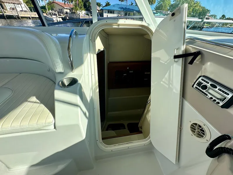 Slide: The Image of 2009 Glacier Bay 3080 boat interior with open cabin door, showcasing seating and control panel. - 14