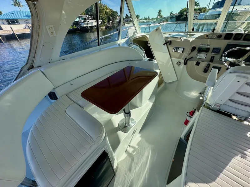 Slide: The Image of Interior of 2009 Glacier Bay 3080 boat with seating and wooden table, docked by the water. - 3