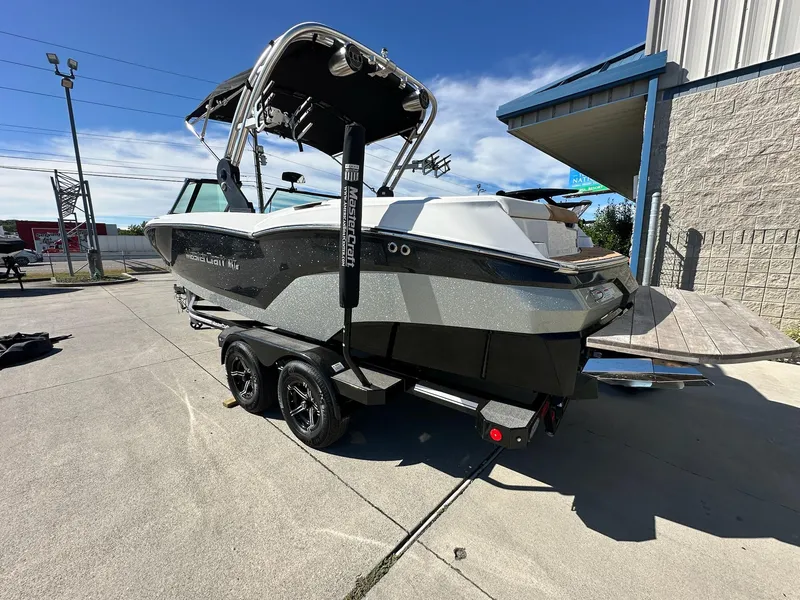 Slide: The Image of 2021 MasterCraft NXT22 boat on trailer, parked outdoors, showcasing sleek design and modern features. - 1