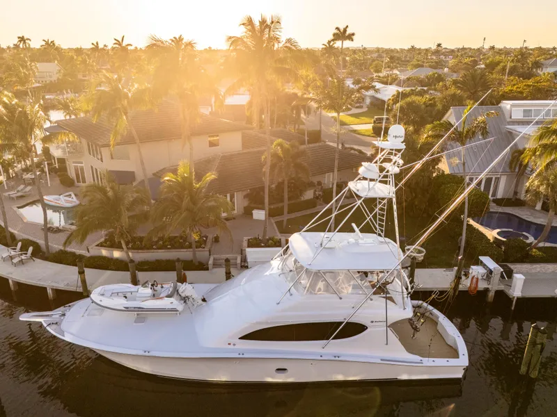 Slide: The Image of 2008 Hatteras 68 Convertible yacht docked at sunset, surrounded by palm trees and waterfront homes. - 5