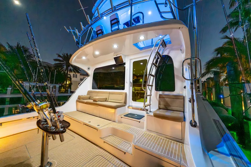 Slide: The Image of 2008 Hatteras 68 Convertible yacht deck with seating and fishing rods at night. - 20