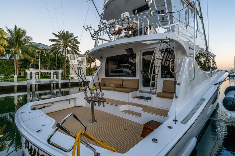 Slide: The Image of 2008 Hatteras 68 Convertible yacht docked, featuring spacious deck and fishing equipment. - 28