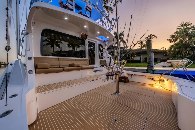 Slide: The Image of 2008 Hatteras 68 Convertible yacht deck at sunset, featuring seating and fishing equipment. - 22