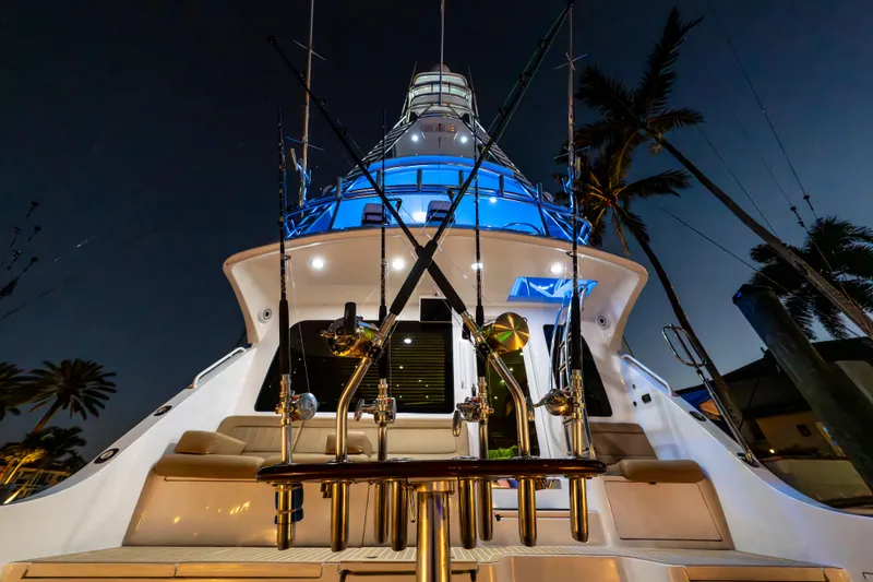 Slide: The Image of 2008 Hatteras 68 Convertible yacht illuminated at night, showcasing fishing rods and sleek design. - 25