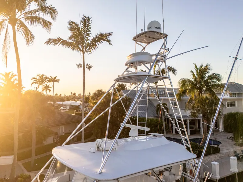 Slide: The Image of 2008 Hatteras 68 Convertible yacht with tower, surrounded by palm trees at sunset. - 46