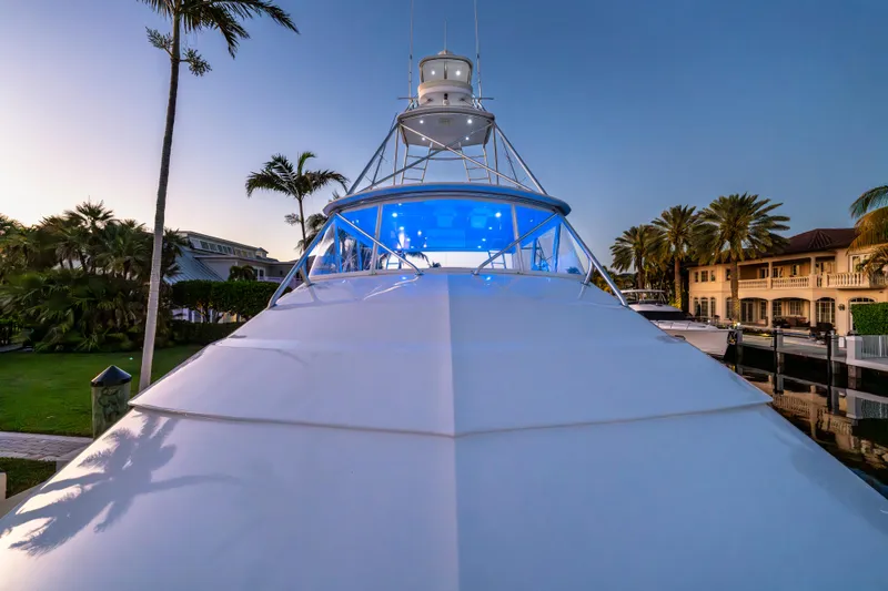 Slide: The Image of 2008 Hatteras 68 Convertible yacht with blue lighting, docked near palm trees at sunset. - 11