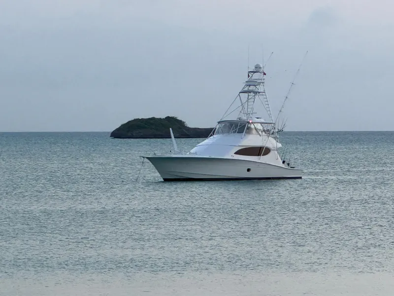 Slide: The Image of 2008 Hatteras 68 Convertible yacht anchored in calm waters near a small island. - 83