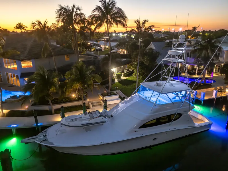 Slide: The Image of Hatteras 68 Convertible yacht docked at sunset, 2008 model, with illuminated water and palm trees. - 2