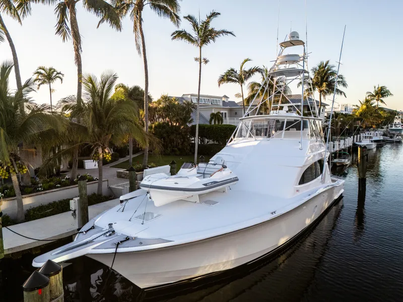 Slide: The Image of 2008 Hatteras 68 Convertible yacht docked by palm trees in a serene marina. - 6