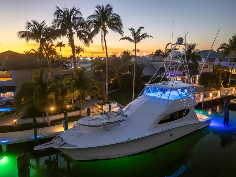 Slide: The Image of 2008 Hatteras 68 Convertible yacht docked at sunset with palm trees and waterfront homes. - 12
