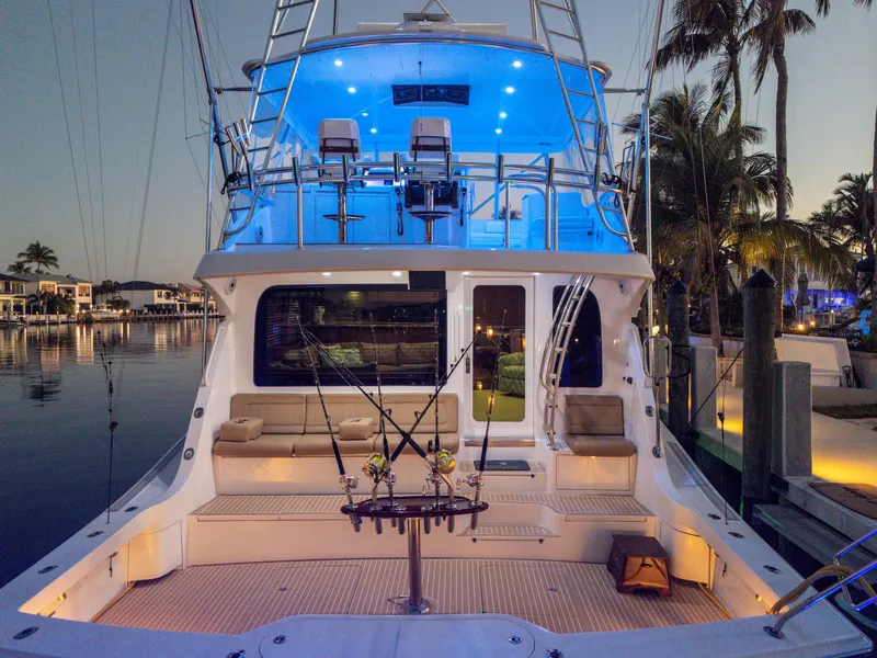 Slide: The Image of 2008 Hatteras 68 Convertible yacht with illuminated deck at sunset, docked near palm trees. - 21