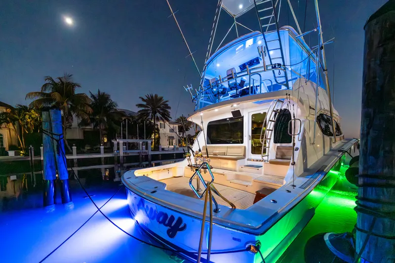 Slide: The Image of 2008 Hatteras 68 Convertible yacht with vibrant underwater lights at night. - 19