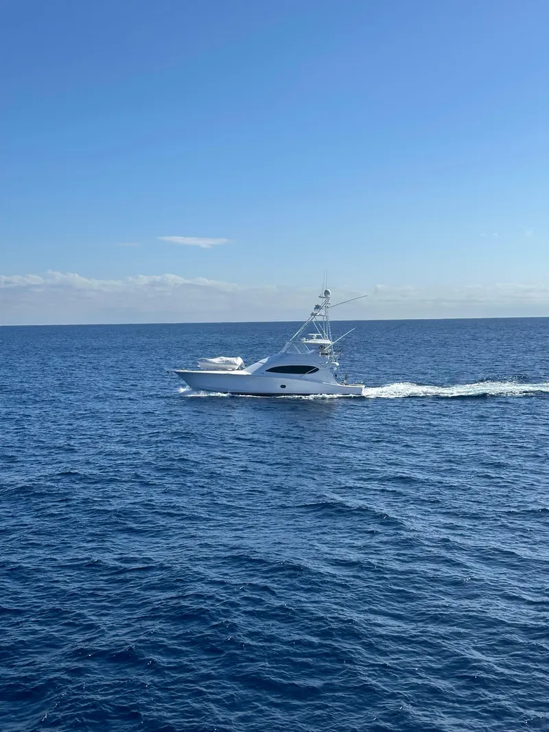 Slide: The Image of 2008 Hatteras 68 Convertible yacht cruising on open sea under clear blue sky. - 81