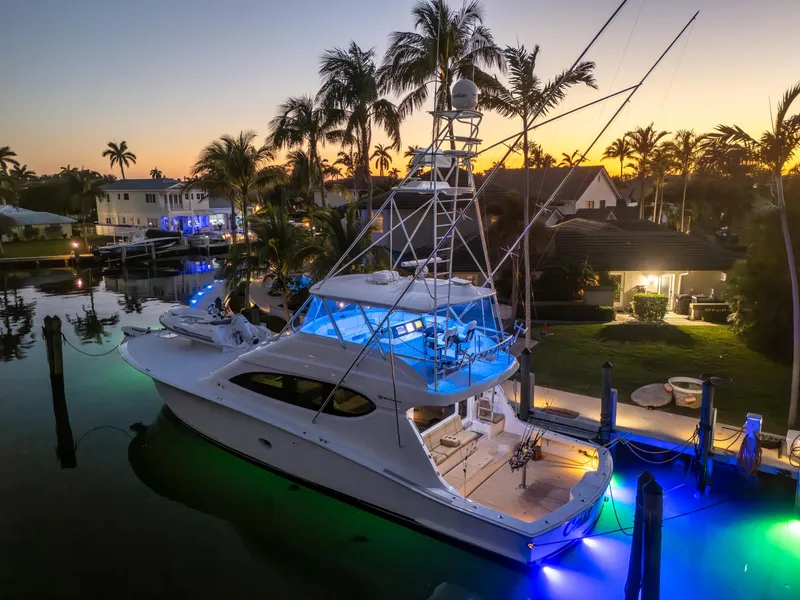 Slide: The Image of 2008 Hatteras 68 Convertible yacht docked at sunset with vibrant underwater lights. - 1