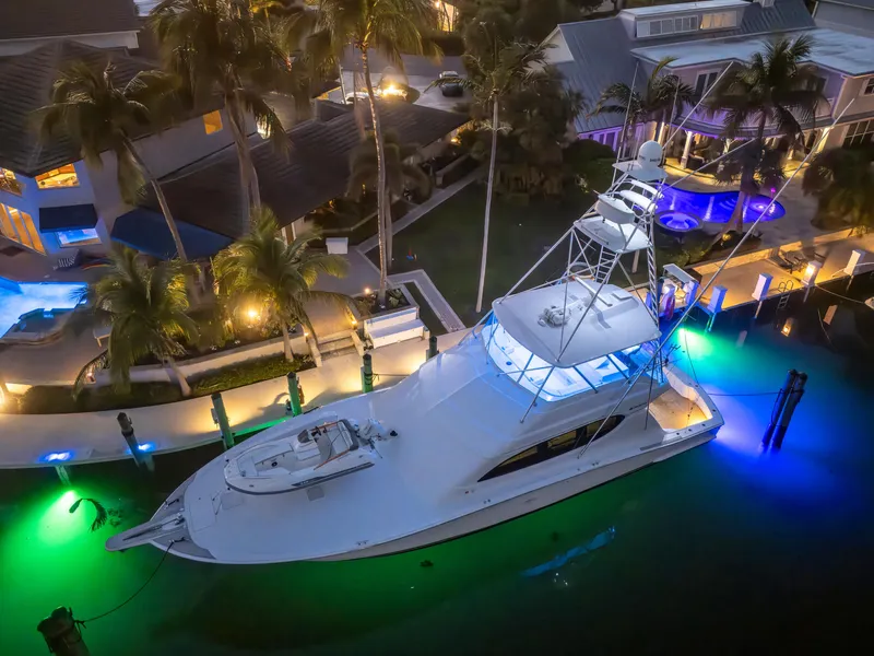 Slide: The Image of 2008 Hatteras 68 Convertible yacht docked, illuminated by vibrant underwater lights. - 14