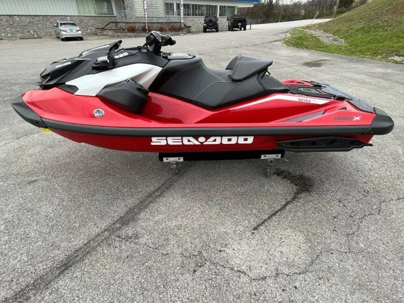 Slide: The Image of 2024 Sea-Doo RXP-X 325 Sound, red and black jet ski, parked on pavement. - 11