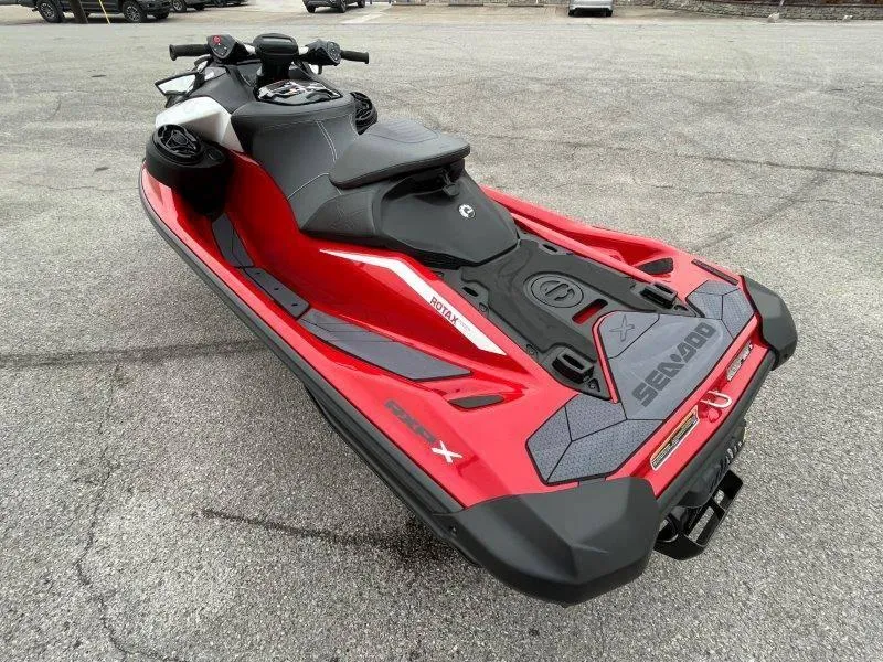 Slide: The Image of 2024 Sea-Doo RXP-X 325 Sound, red and black jet ski, parked on pavement. - 5