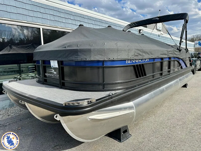 Slide: The Image of 2024 Bennington 23 LXFB pontoon boat with cover, docked outdoors. - 14