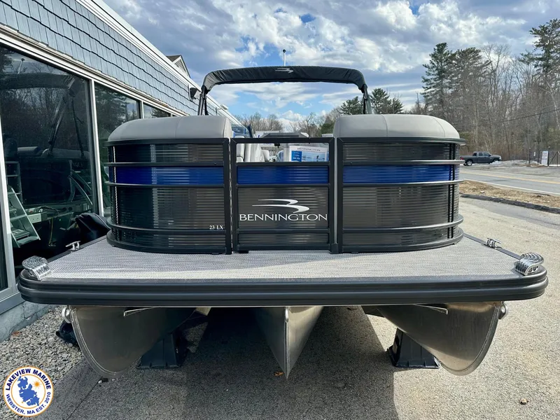 Slide: The Image of 2024 Bennington 23 LXFB pontoon boat, sleek design, parked outdoors under cloudy sky. - 2