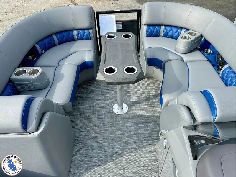 Slide: The Image of 2024 Bennington 23 LXFB boat interior with gray and blue seating, cup holders, and table. - 3