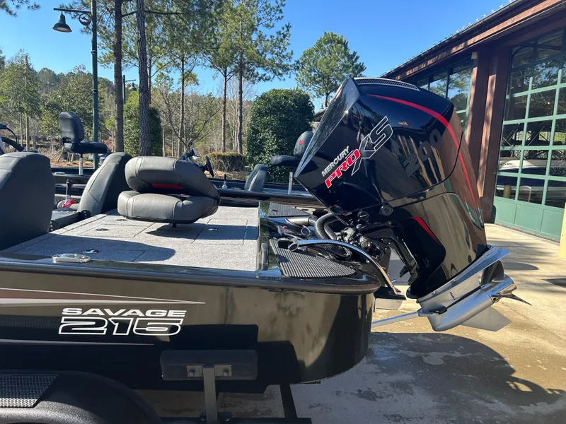 Slide: The Image of 2025 Tracker Savage 215 boat with powerful outboard motor, parked outdoors. - 2