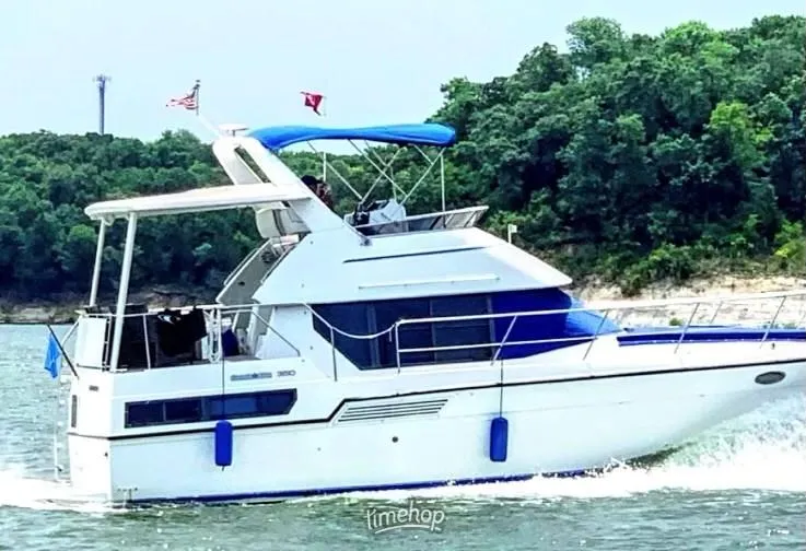 Slide: The Image of 1994 Carver 350 Aft Cabin yacht cruising on a lake with lush green shoreline. - 3