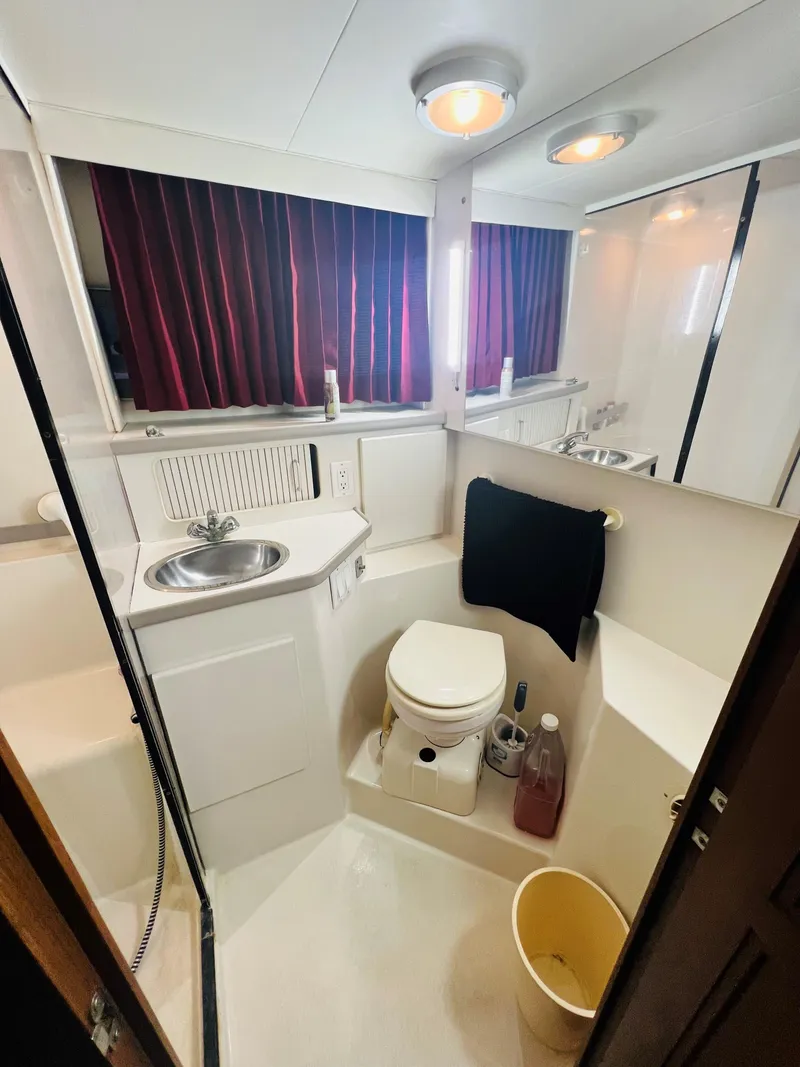 Slide: The Image of 1994 Carver 350 Aft Cabin bathroom with sink, toilet, and red curtains. - 34