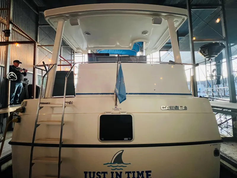 Slide: The Image of 1994 Carver 350 Aft Cabin yacht in a marina, rear view with ladder and name "Just In Time." - 5