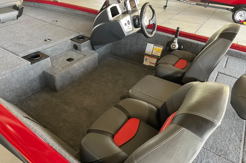 Slide: The Image of 2025 Tracker Pro Team 190 boat interior with gray and red seating, steering console, and carpeted flooring. - 4