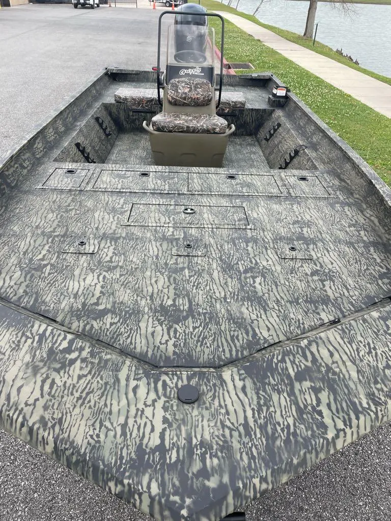 Slide: The Image of 2025 Tracker Grizzly 2072 CC boat with camouflage design, parked near a waterfront. - 3