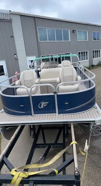 Slide: The Image of 2022 Forester 2208CC pontoon boat on trailer, parked outside industrial building. - 6