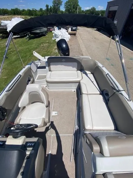 Slide: The Image of 2019 Crownline E 205 XS boat interior with seating and canopy, docked outdoors. - 7