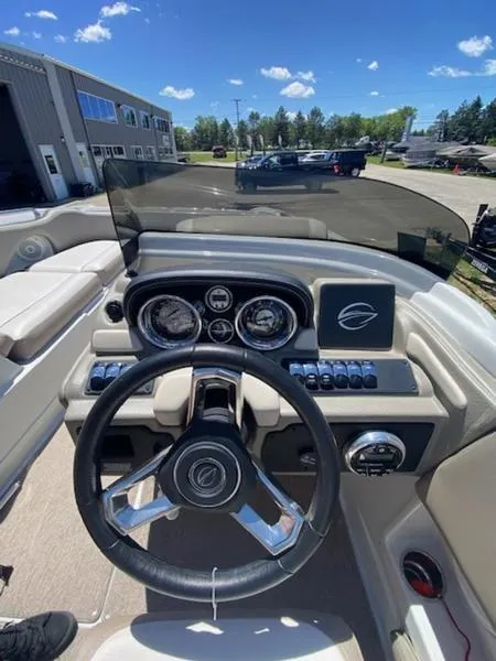 Slide: The Image of 2019 Crownline E 205 XS boat dashboard with steering wheel and gauges, parked outdoors. - 8
