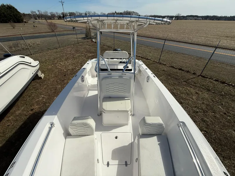 Slide: The Image of 2023 Aquasport 22CC boat with spacious deck and seating, parked outdoors. - 6
