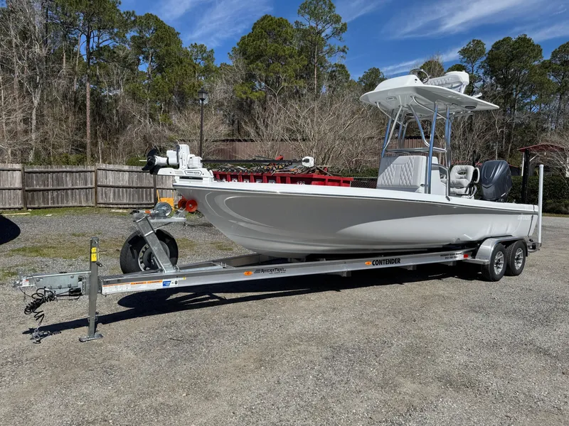 The Image of 2025 Contender 26 Bay boat on trailer, parked outdoors with trees in the background. - 1