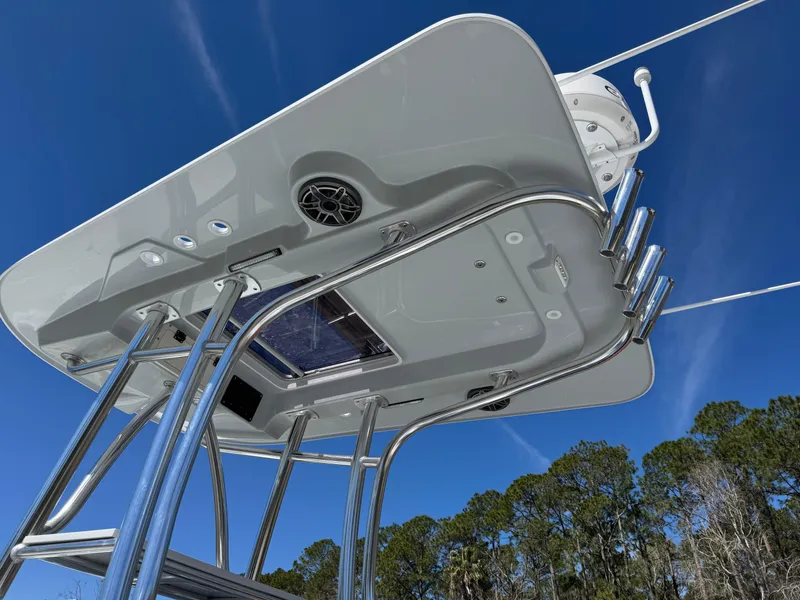 Slide: The Image of 2025 Contender 26 Bay boat's T-top with rod holders and speaker, under clear blue sky. - 24