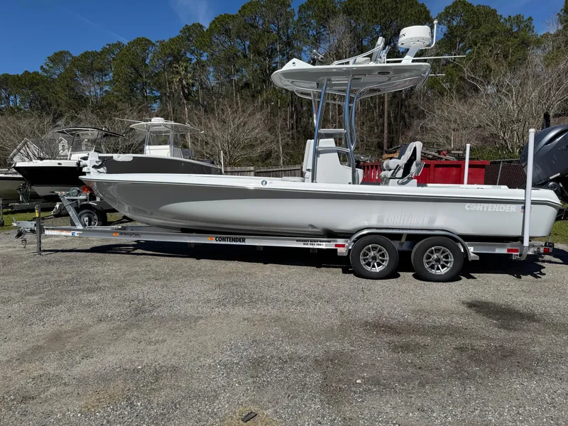Slide: The Image of 2025 Contender 26 Bay boat on trailer, parked outdoors, surrounded by trees. - 3
