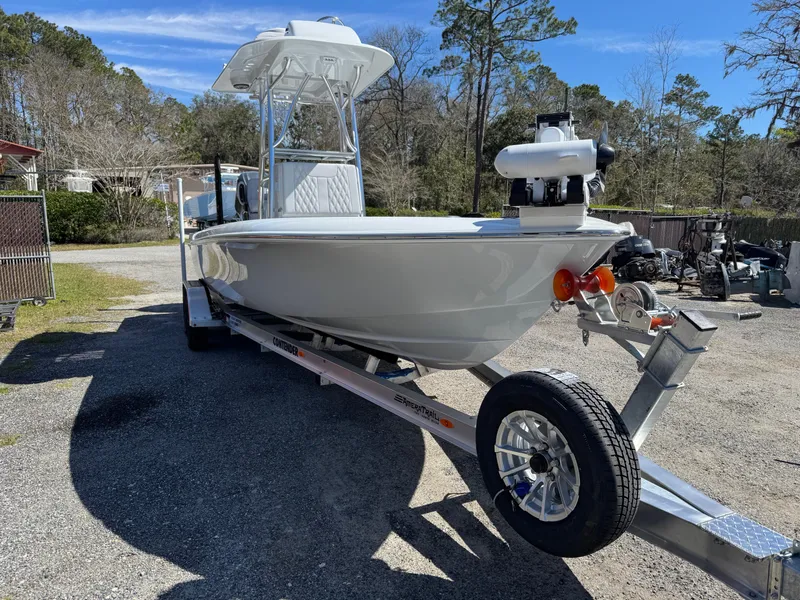 Slide: The Image of 2025 Contender 26 Bay boat on trailer, parked outdoors, under clear blue sky. - 6