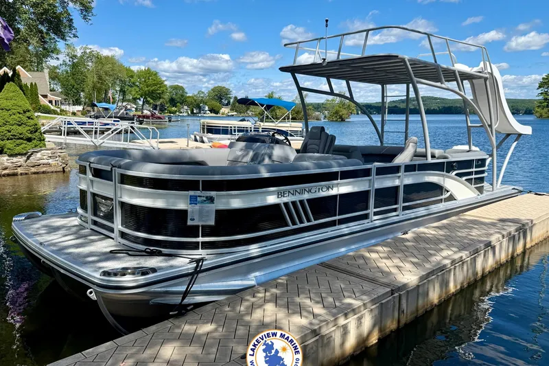 The Image of 2025 Bennington 26 LSRTD pontoon boat docked on a sunny lake. - 0