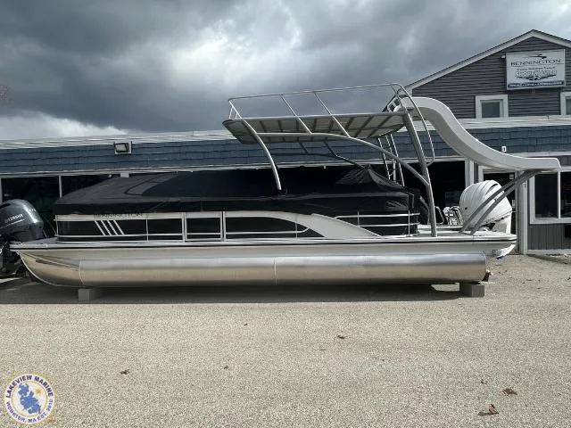 Slide: The Image of 2025 Bennington 26 LSRTD pontoon boat with slide, parked outdoors under cloudy skies. - 21