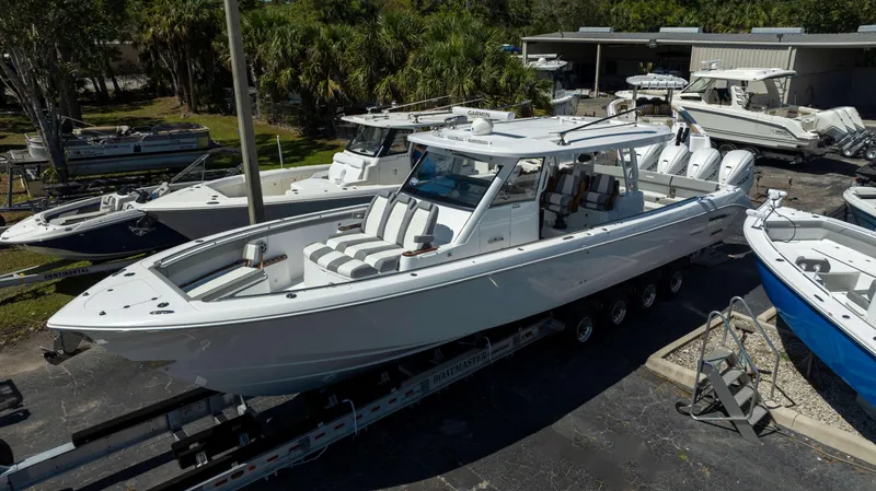 Slide: The Image of 2025 Everglades 455 CC boat on trailer, surrounded by other boats in a marina. - 1