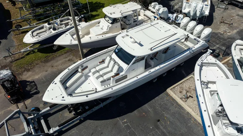 Slide: The Image of 2025 Everglades 455 CC boat on trailer, surrounded by other boats in a lot. - 2