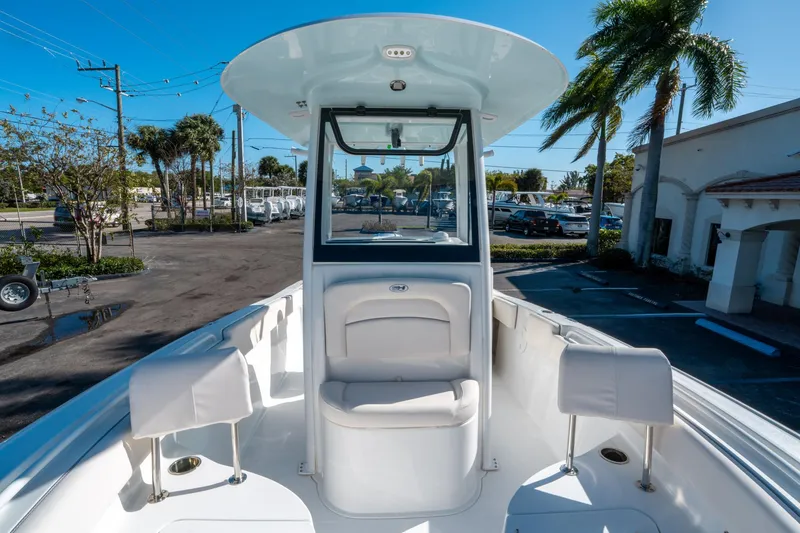 Slide: The Image of 2025 Sea Hunt Ultra 235 SE boat interior with seating, parked outdoors. - 25