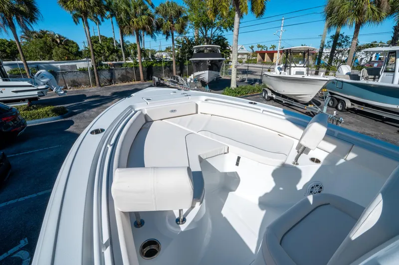 Slide: The Image of 2025 Sea Hunt Ultra 235 SE boat interior with seating, parked outdoors under palm trees. - 20